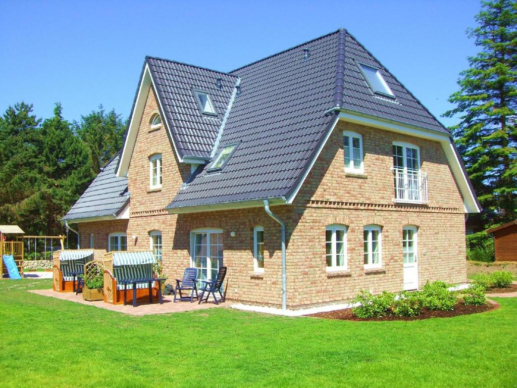 a large brick house with a black roof at Sonnendeck - Hüs in Lee in Süddorf