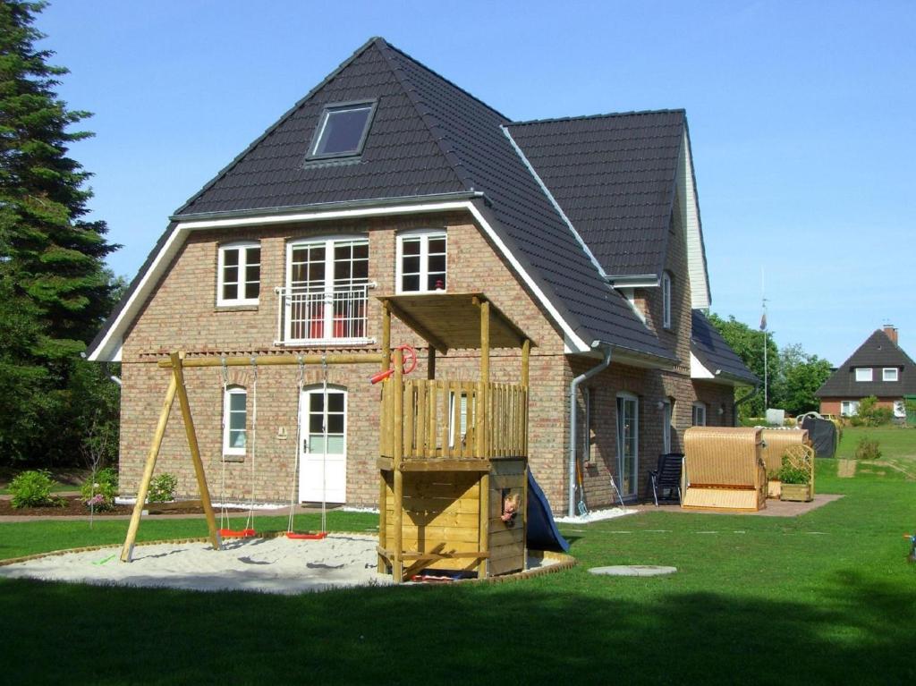 a house with a playground in front of it at Ausguck - Hüs in Lee in Süddorf