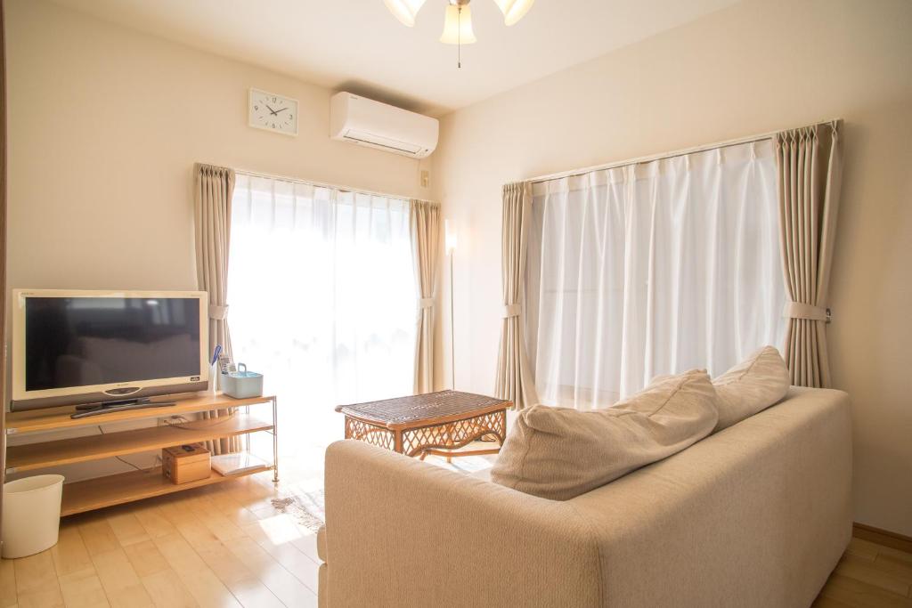 a living room with a couch and a television at RIVERSIDE INN KAMAKURA in Kamakura