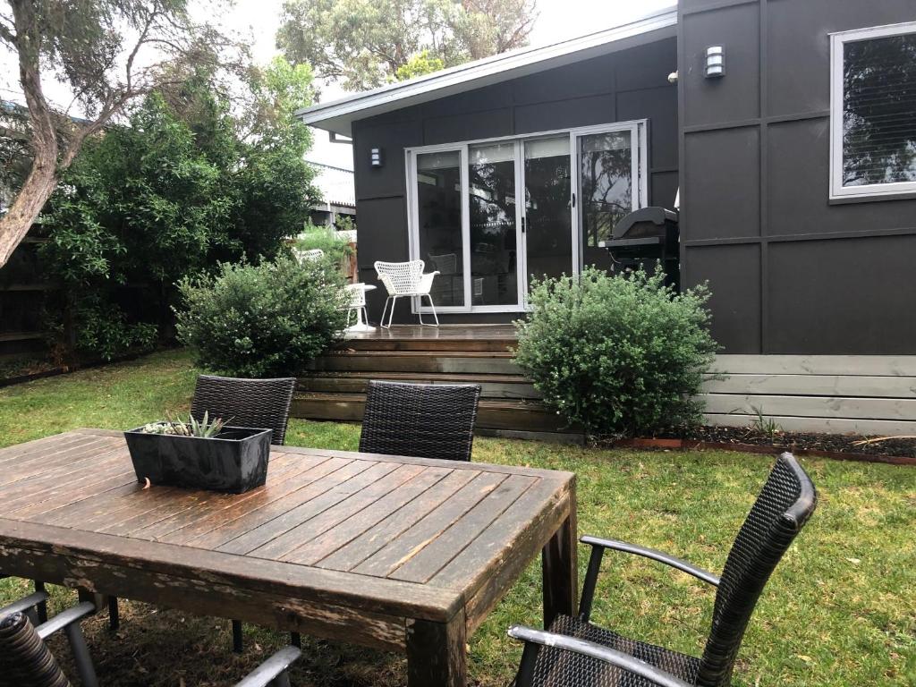 a wooden table and chairs in front of a house at Tamara Beach House in Inverloch