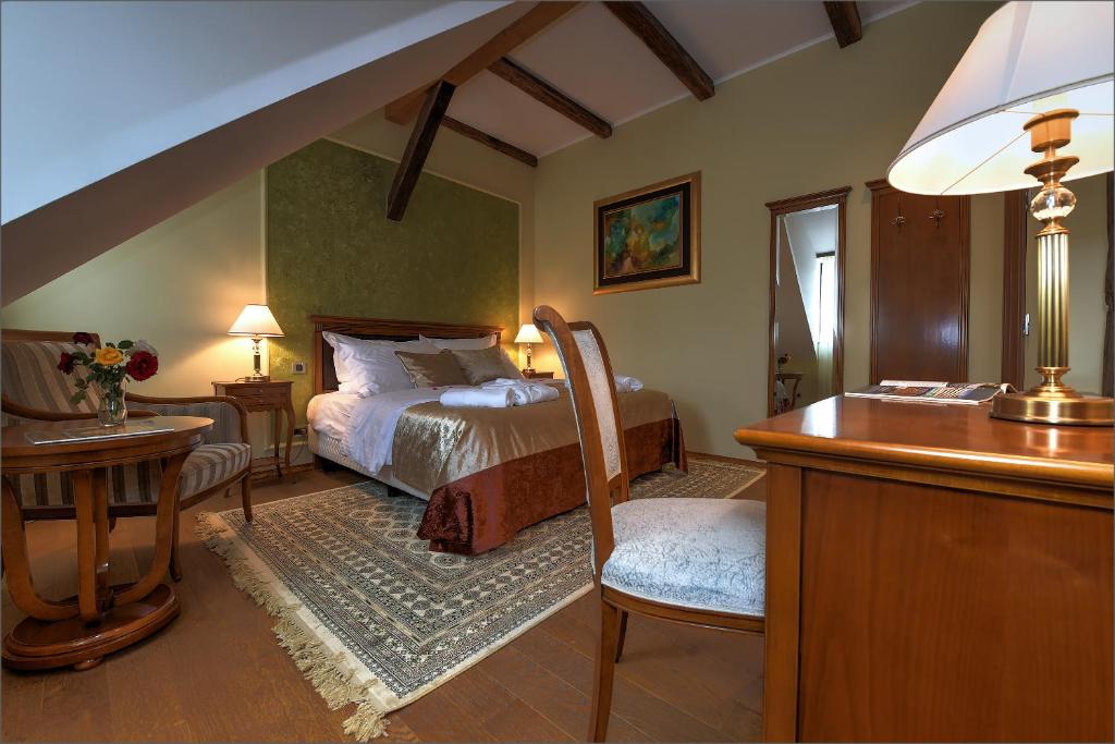 a bedroom with a bed and a desk with a desk at Hotel Dvorac Jurjevec in Lekenik