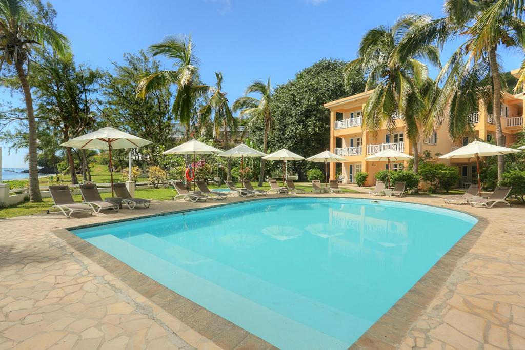 una gran piscina con sillas y sombrillas en Cocotiers Hotel - Rodrigues, en Rodrigues Island
