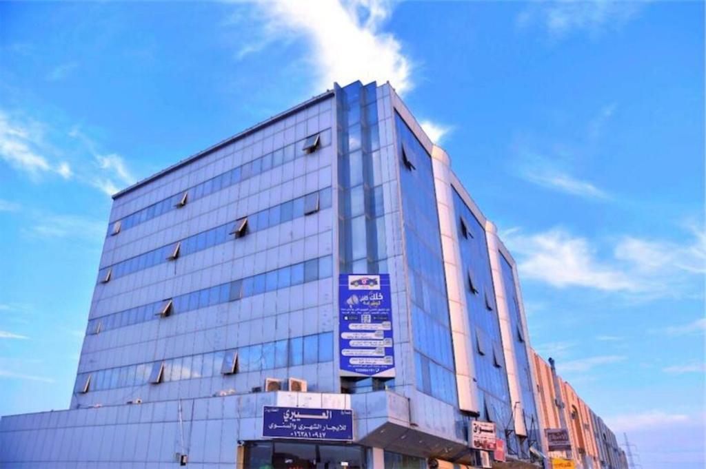 un grand bâtiment bleu avec des panneaux sur son côté dans l'établissement Al Eairy Apartment-Alqaseem 4, à Buraydah
