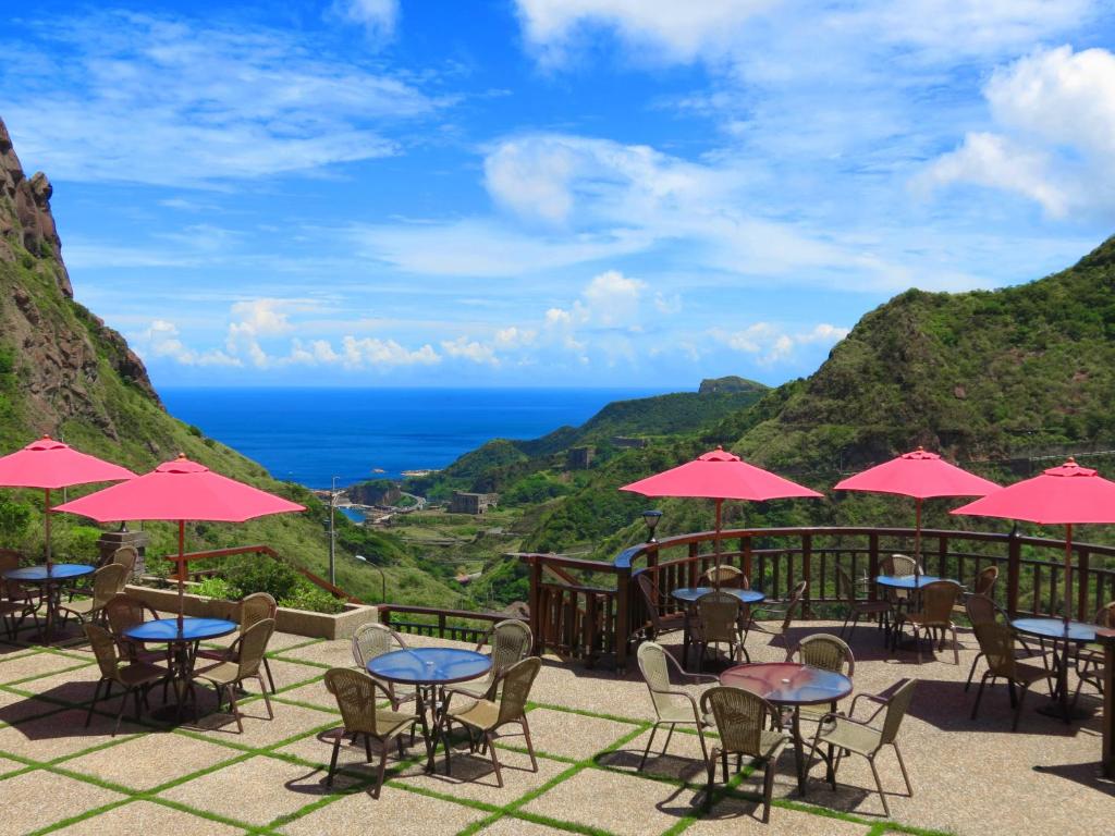 a patio with tables and chairs with a view of the ocean at Formosa Arcadian Villa in Jiufen