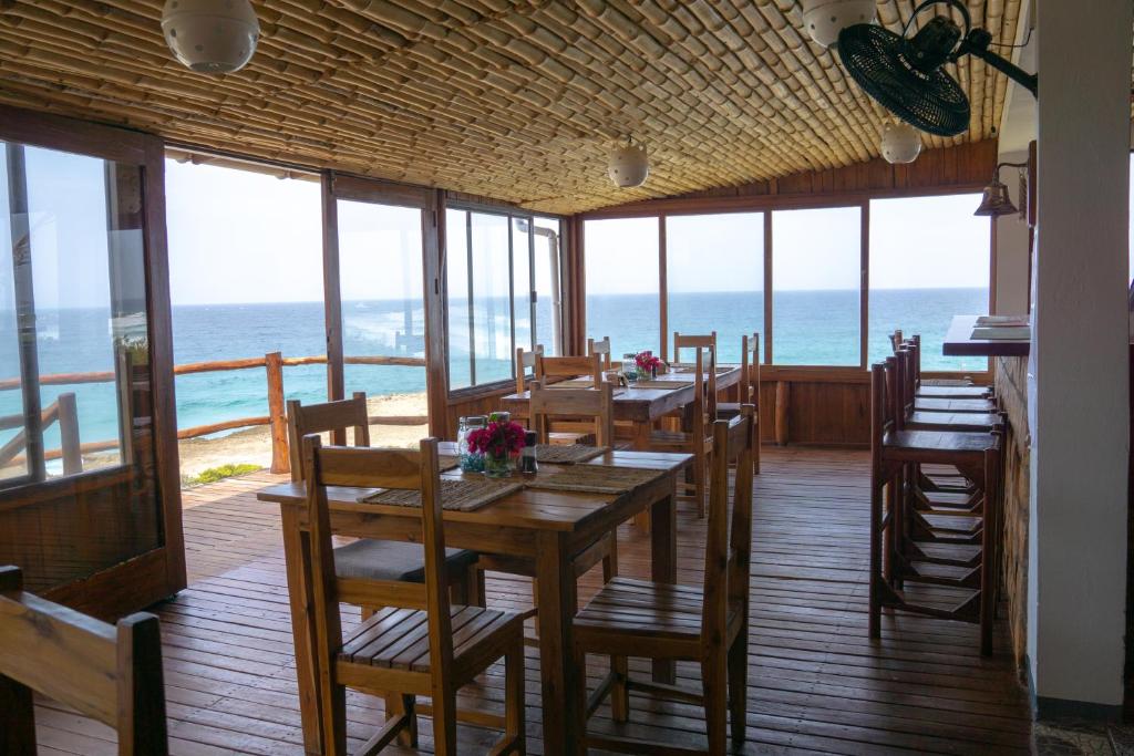 a dining room with a table and chairs and the ocean at C-Mew Guest House in Praia do Tofo