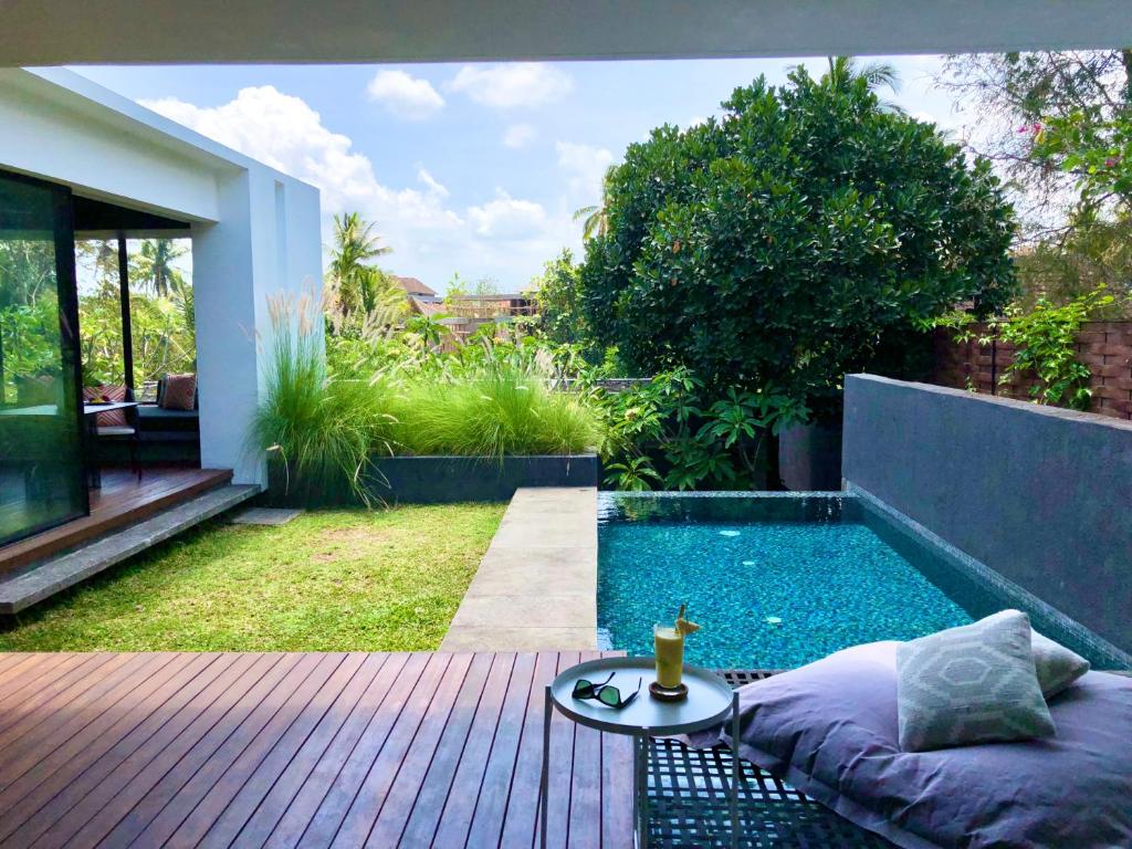 a small swimming pool in a backyard with a table at Origin Ubud in Ubud