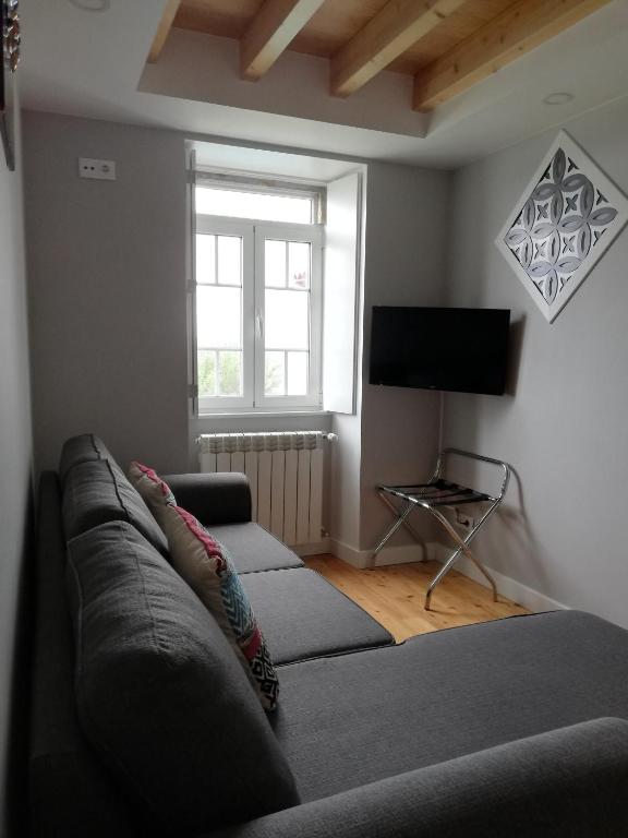 a living room with a couch and a television at Chalet O Amorzinho Sintra Praia in Sintra