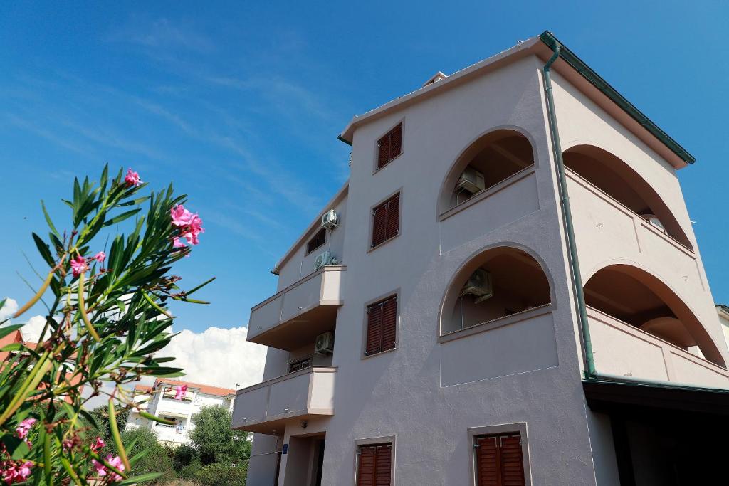 ein weißes Gebäude mit Balkonen und einem Baum in der Unterkunft Apartments Dario in Novalja