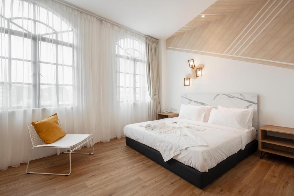 a bedroom with a large bed and a chair at One Heritage Hotel in Seremban