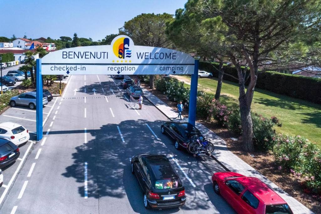 a parking lot with cars parked under a welcome sign at Villaggio San Francesco in Duna Verde