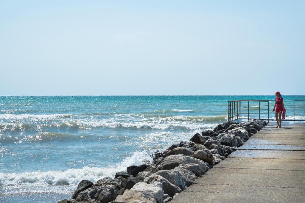 a woman walking on a pier near the ocean at Villaggio San Francesco in Duna Verde