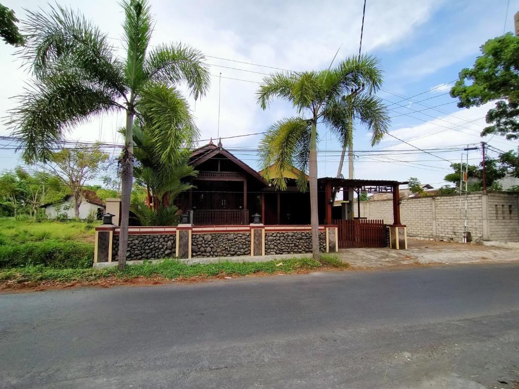 a house with palm trees in front of a street at Jati Classic Homestay in Banyuwangi