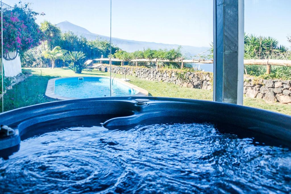 a hot tub in a yard with a pool of water at Casa Las Riquelas in Sauzal
