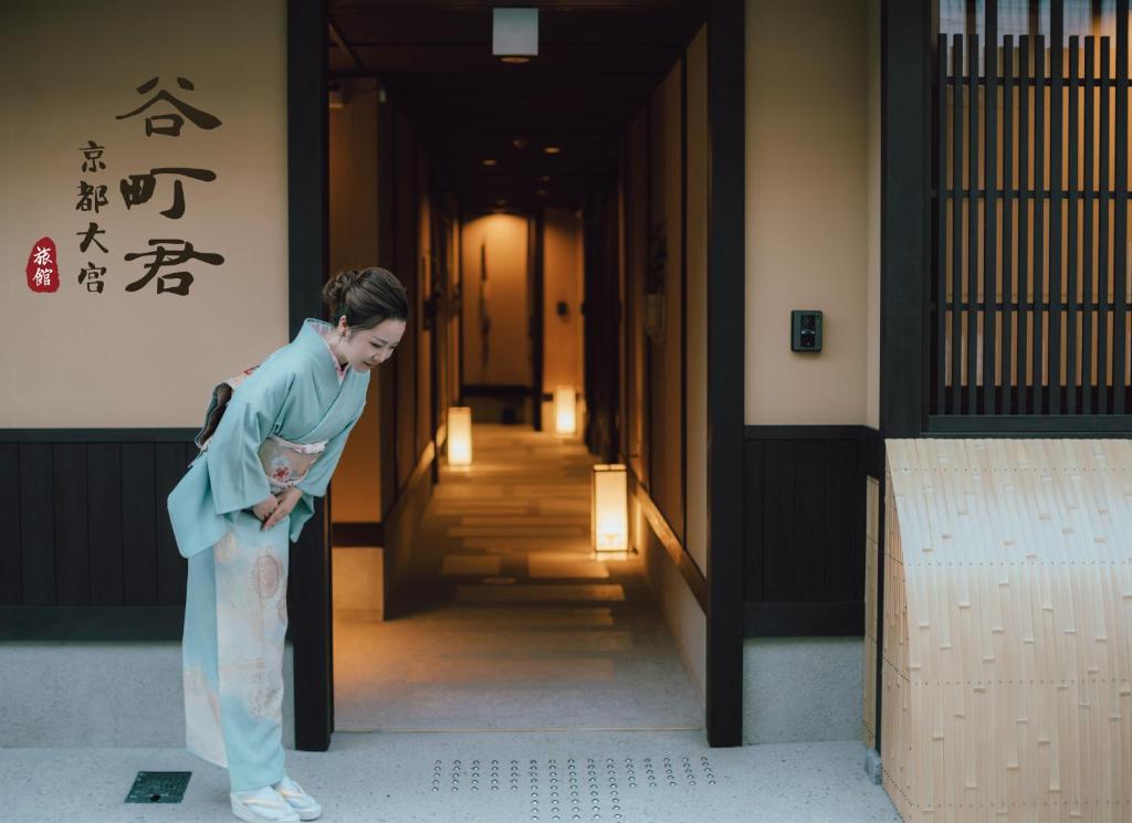 a woman in a kimono standing in a hallway at 谷町君 星屋 大宮旅館 京都四条大宮 in Kyoto