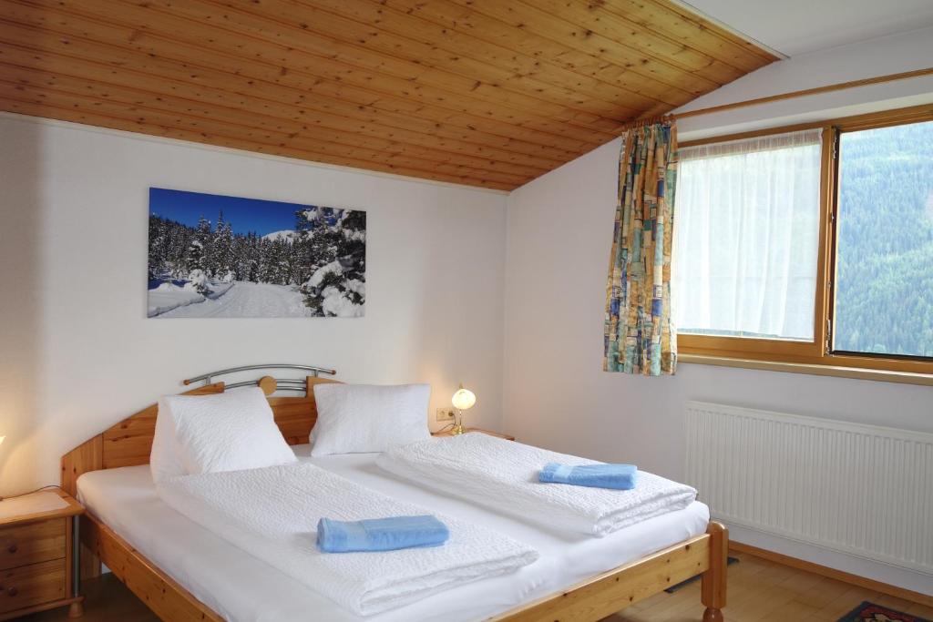 a bedroom with a bed with white sheets and a window at Landhaus Dangl in Fliess