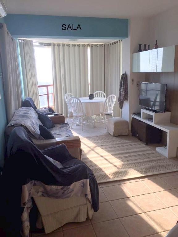 Sala de estar con cama y mesa con TV en apartamento 4 praças, en Torres