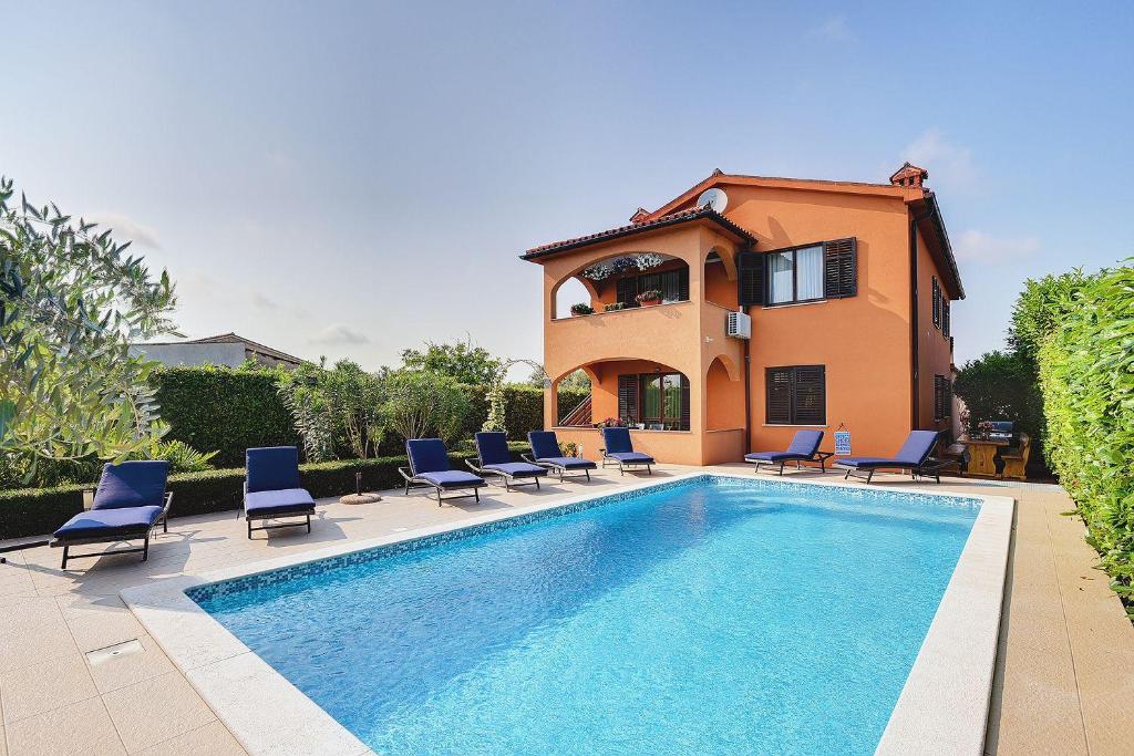 een villa met een zwembad met stoelen en een huis bij Casa Sissano in Šišan