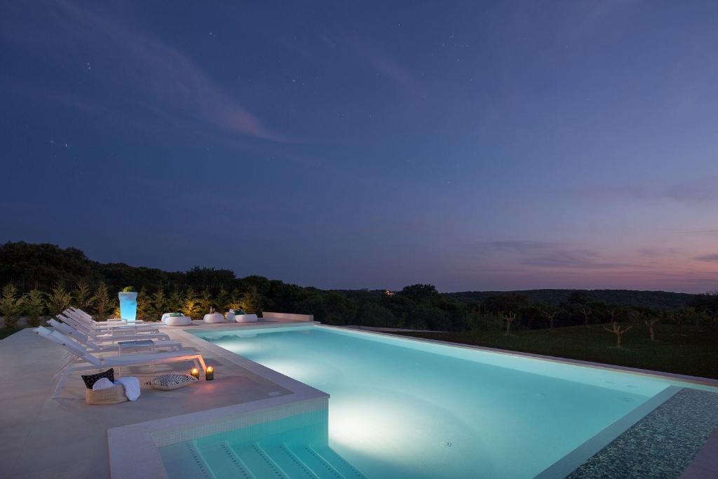 a swimming pool at night with lounge chairs at Villa PS Deluxe in Pula