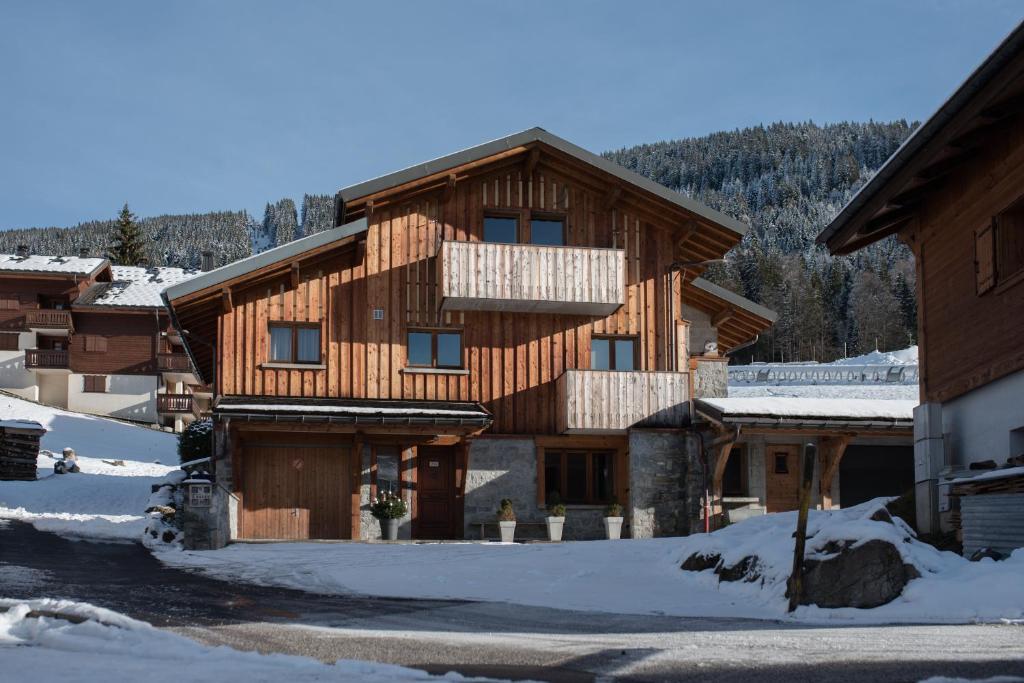 a large wooden house with snow on the ground at Chalet 4M Les Carroz et son Spa in Les Carroz d'Araches