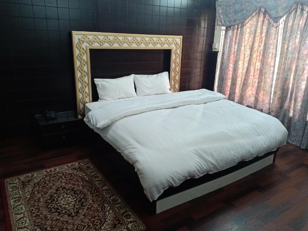 een bed met witte lakens en kussens in een slaapkamer bij New Islamabad Guest House in Islamabad