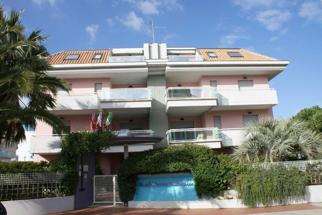 ein rosafarbenes Gebäude mit einer Palme davor in der Unterkunft Appartamento Mediterraneo in San Benedetto del Tronto