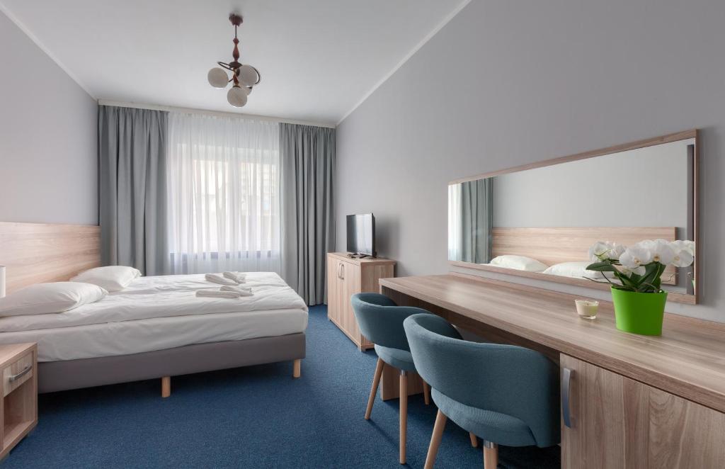ミエンジズドロイェにあるPosejdonのベッドと大きな鏡が備わるホテルルームです。