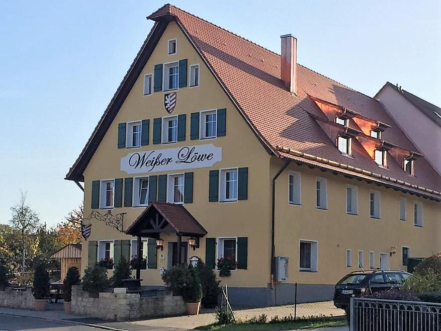 un gran edificio amarillo con un cartel. en Weißer Löwe en Burgthann