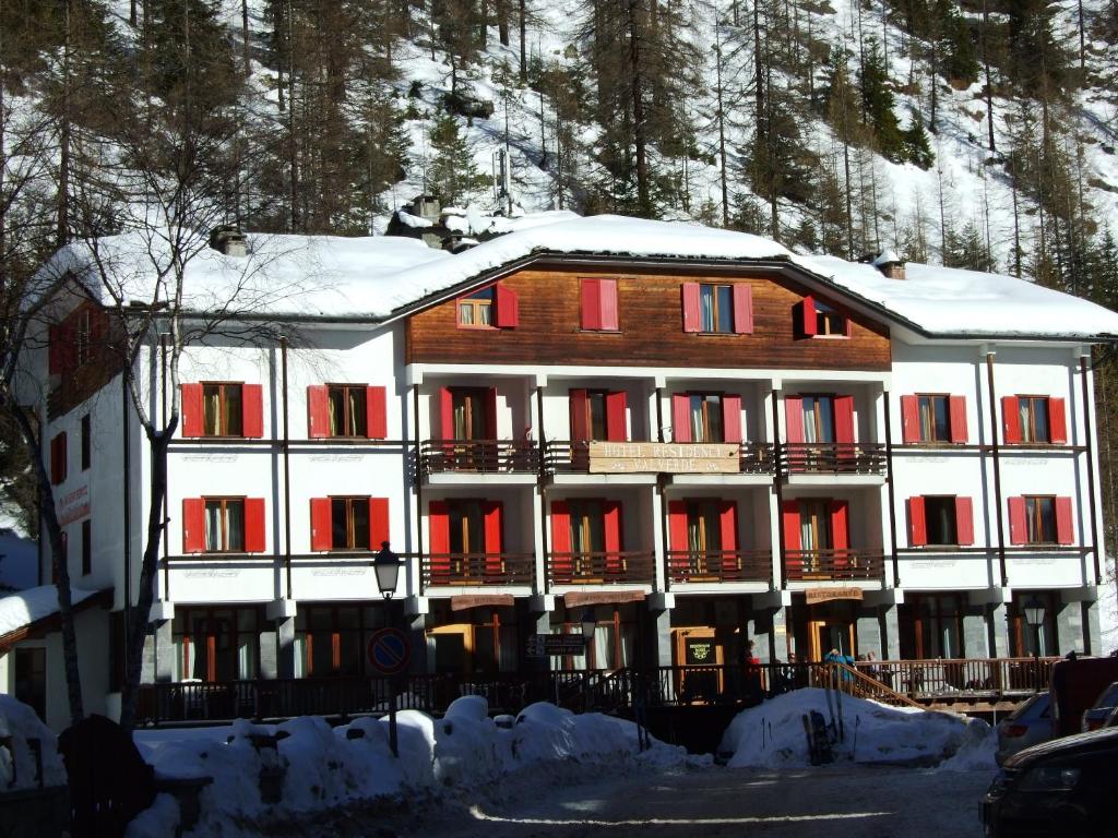 a large building with red doors and snow on it at Hotel Valverde in Gressoney-la-Trinité