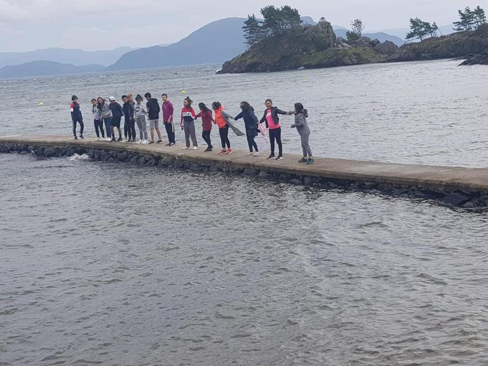 a group of people standing on a dock in the water at Sponavik Camping in Stord