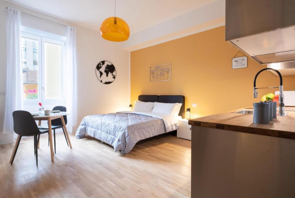 a bedroom with a bed and a table and a kitchen at Residence delle Erbe by Studio Vita in Bologna