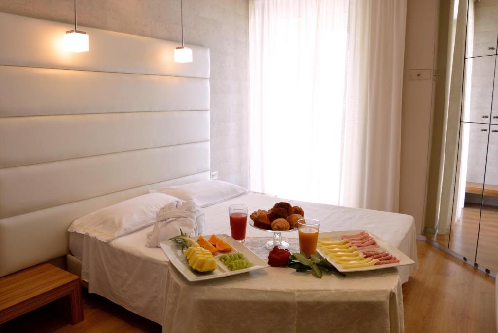 a table with two plates of food on a bed at AmbientHotels Panoramic in Rimini