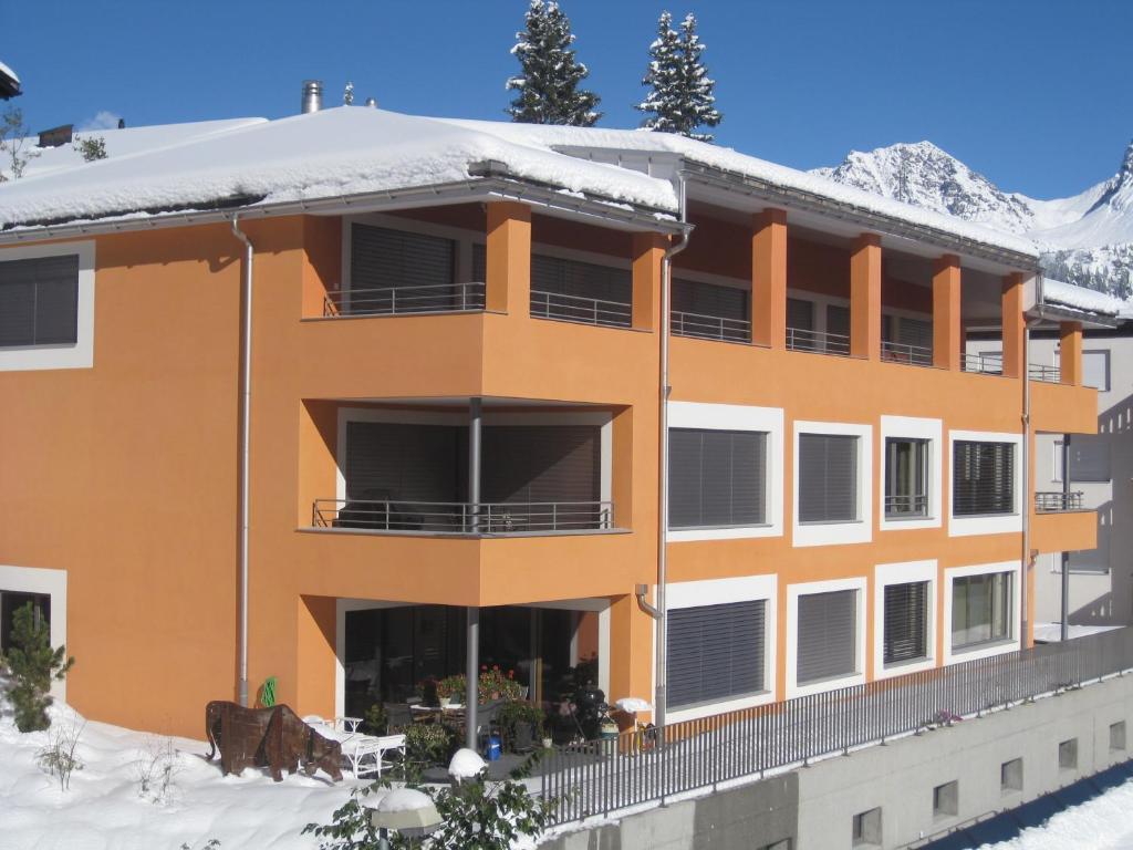ein orangefarbenes Gebäude mit Schnee auf dem Dach in der Unterkunft Pradin 1 in Arosa