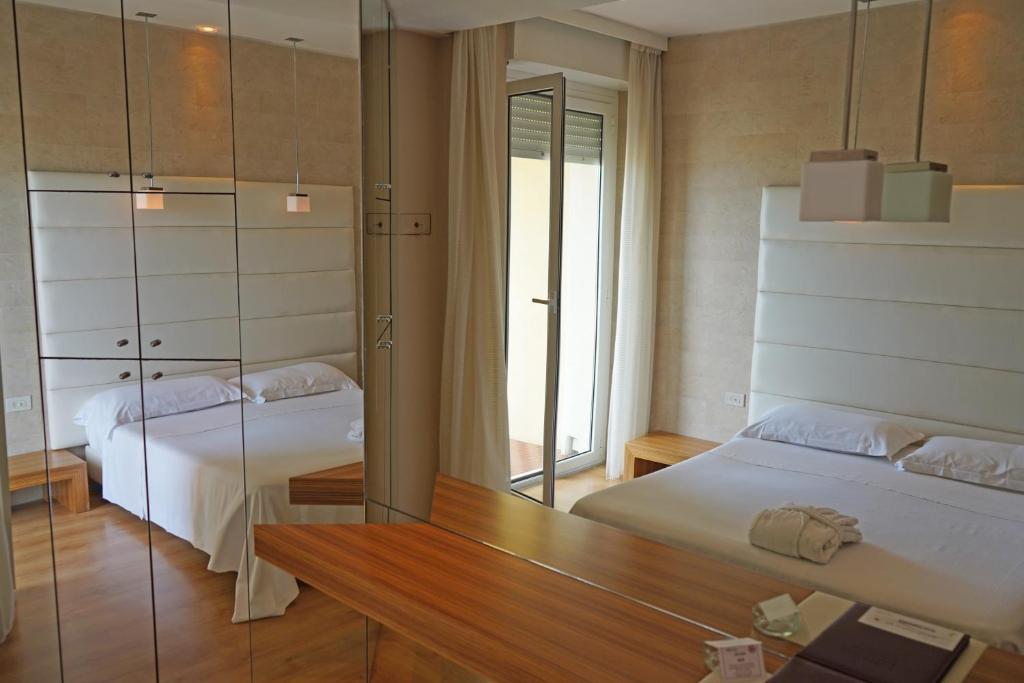 a bedroom with two beds and a mirror at AmbientHotels Panoramic in Rimini