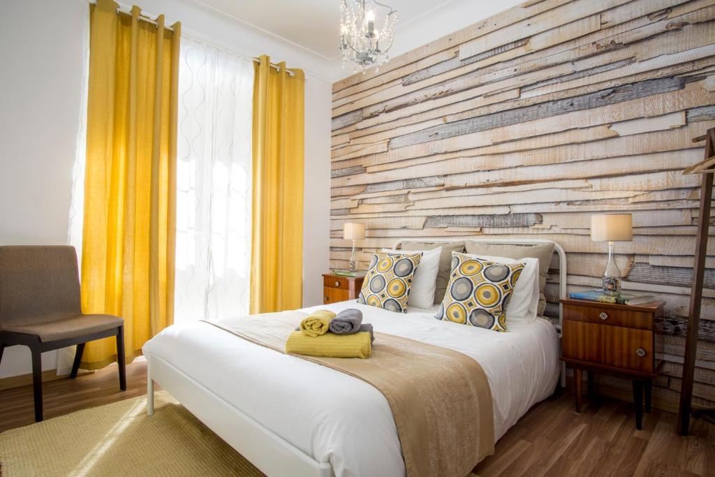 - une chambre avec un grand lit et un mur en bois dans l'établissement Sunny Apartment in a typical Lisbon neighborhood, à Lisbonne