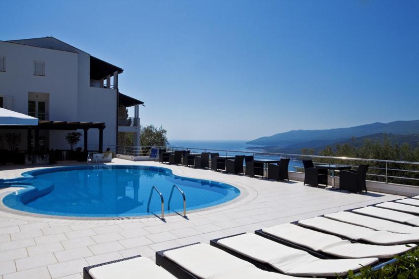 a swimming pool with lounge chairs and the ocean at Hotel Villa Annette in Rabac