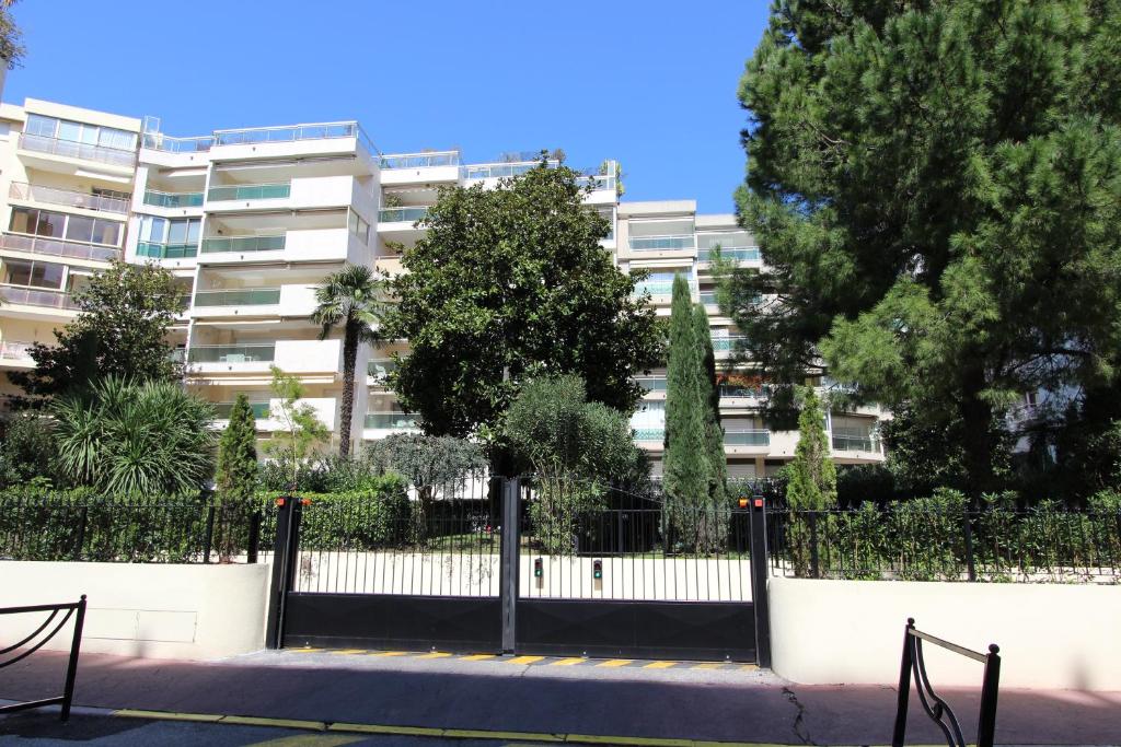 une clôture devant un bâtiment arboré dans l'établissement Appartements de Standing Cannes Centre, à Cannes