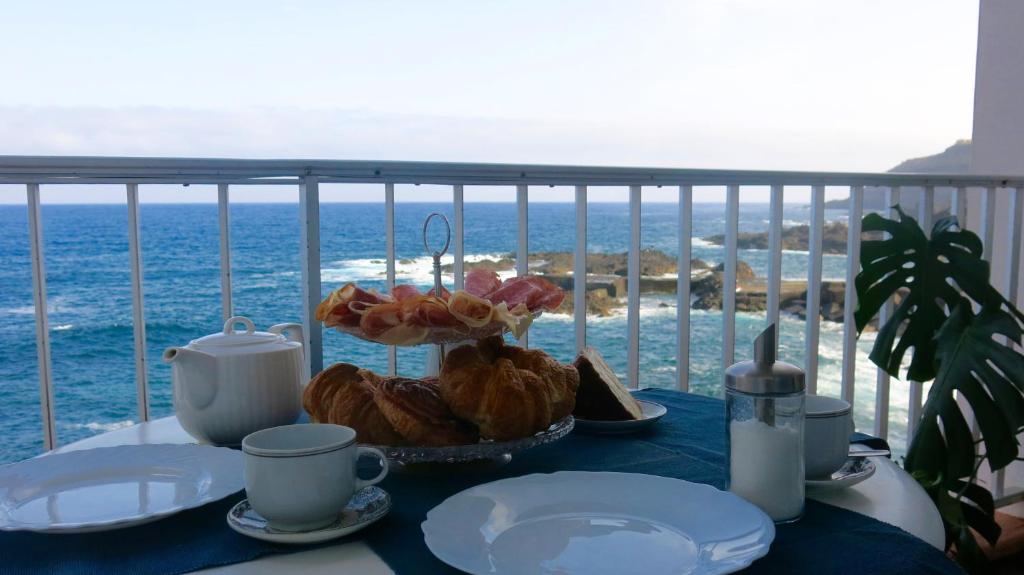 una mesa con pastas y tazas en un balcón con vistas al océano en El Roque 205 - Sustainability off the Beaten Track, en Tacoronte