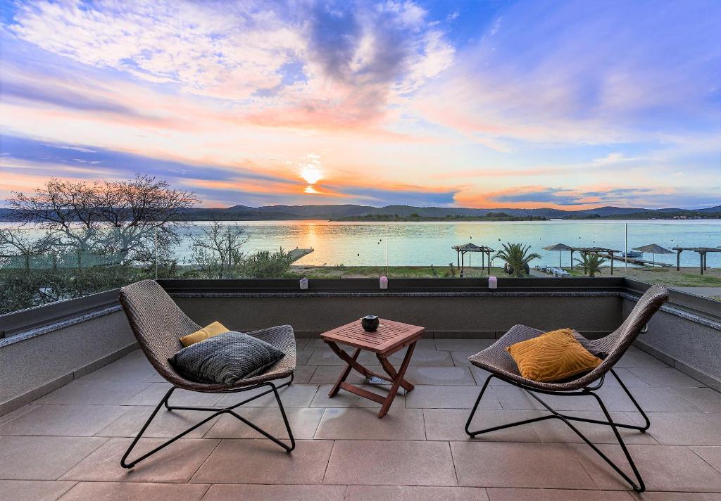 2 Stühle und ein Tisch auf einem Balkon mit Blick auf den Sonnenuntergang in der Unterkunft Villa Lu-Ma in Turanj