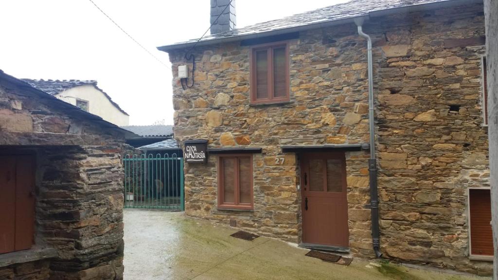 una antigua casa de piedra con puertas marrones y una puerta en Casa Nastasia, en A Pontenova