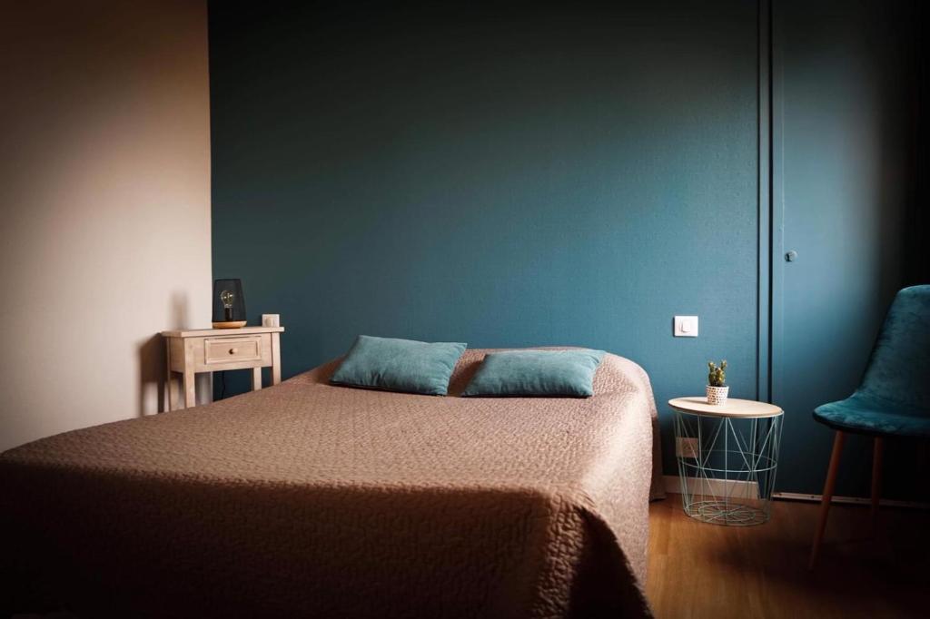 1 dormitorio con cama y pared azul en Hôtel Les Jardins du Lac, en Autun