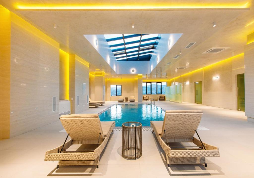 a pool in a building with chairs and a ceiling at Hotel Tbilisi Tower in Tbilisi City