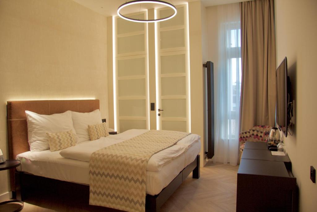 Habitación de hotel con cama y lámpara de araña. en Chevron Hotel en Praga
