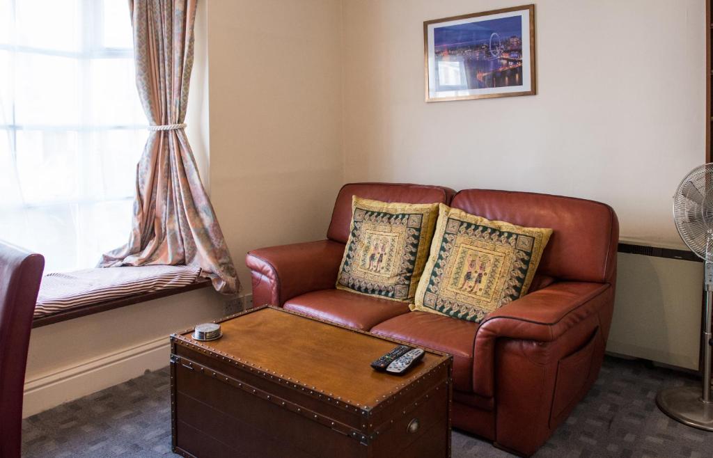 a living room with a brown leather couch and a window at Town Centre Apartment in Leamington Spa