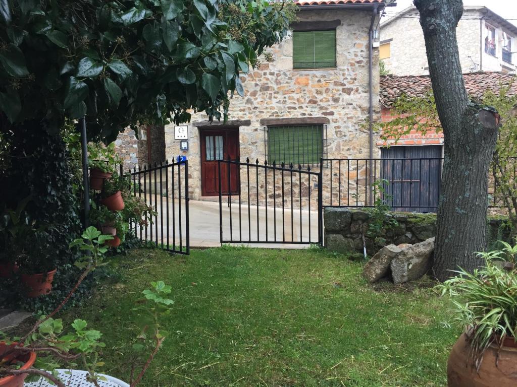 una puerta de hierro delante de una casa con un árbol en Casa Rural El Fortin en Gata