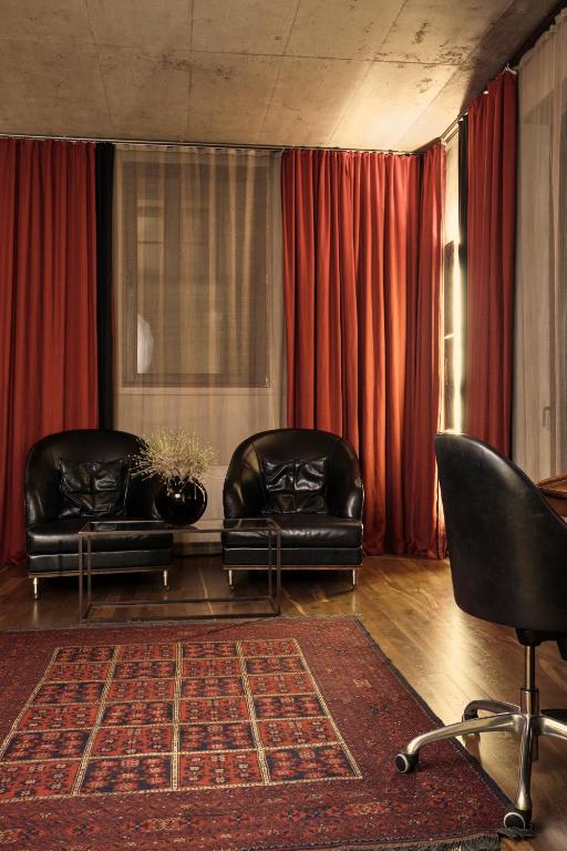 a living room with two leather chairs and a rug at Hotel Stary in Kraków
