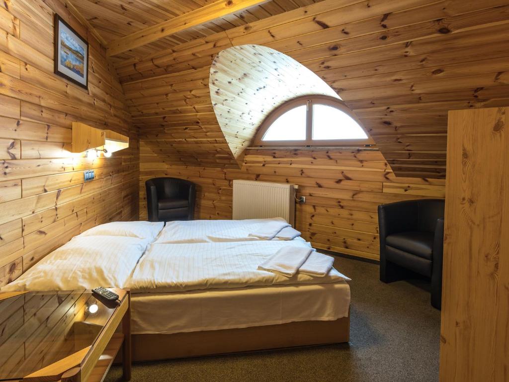 sypialnia z łóżkiem z 2 krzesłami i oknem w obiekcie EA Horský Hotel Hájenka w mieście Modrava