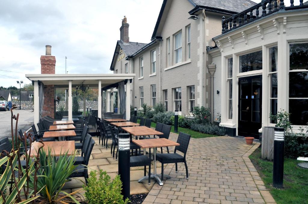 een patio met tafels en stoelen voor een gebouw bij Talardy, St Asaph by Marston’s Inns in St Asaph