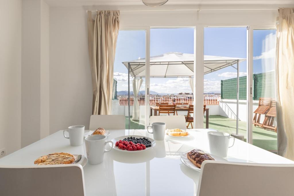 une salle à manger blanche avec une table et de la nourriture dans l'établissement HOMEABOUT LA MERCED Duplexes, à Malaga