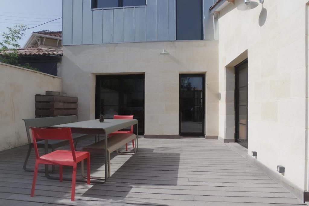 a table and red chairs on a patio at L'Echoppe - Maison 3 chambres avec 2 salles de bain et grande Terrasse in Talence