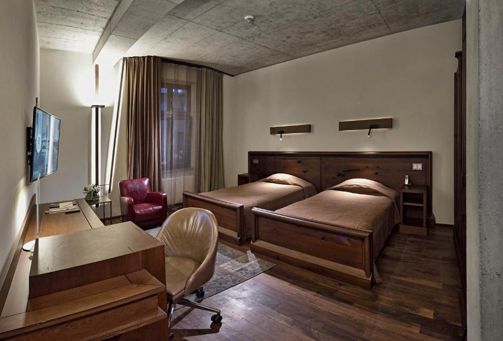 a bedroom with two beds and a desk and a chair at Hotel Stary in Kraków